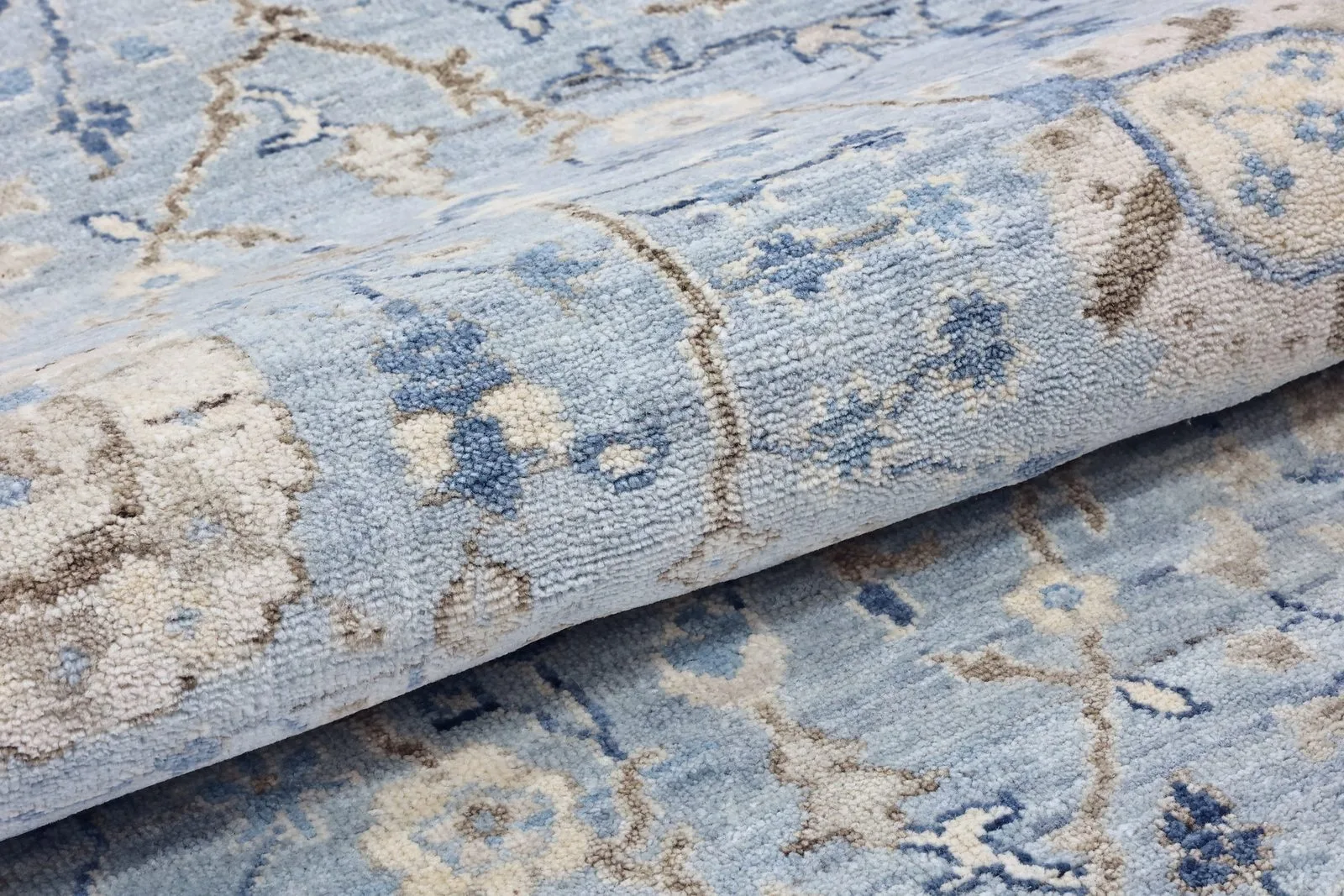 Pale blue hand-knotted rug folded to show the pile