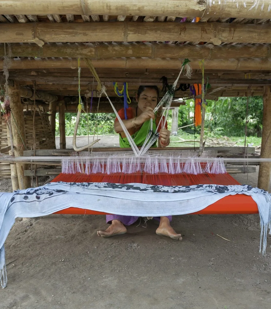 A weaver working a handloom in a daylight workshop