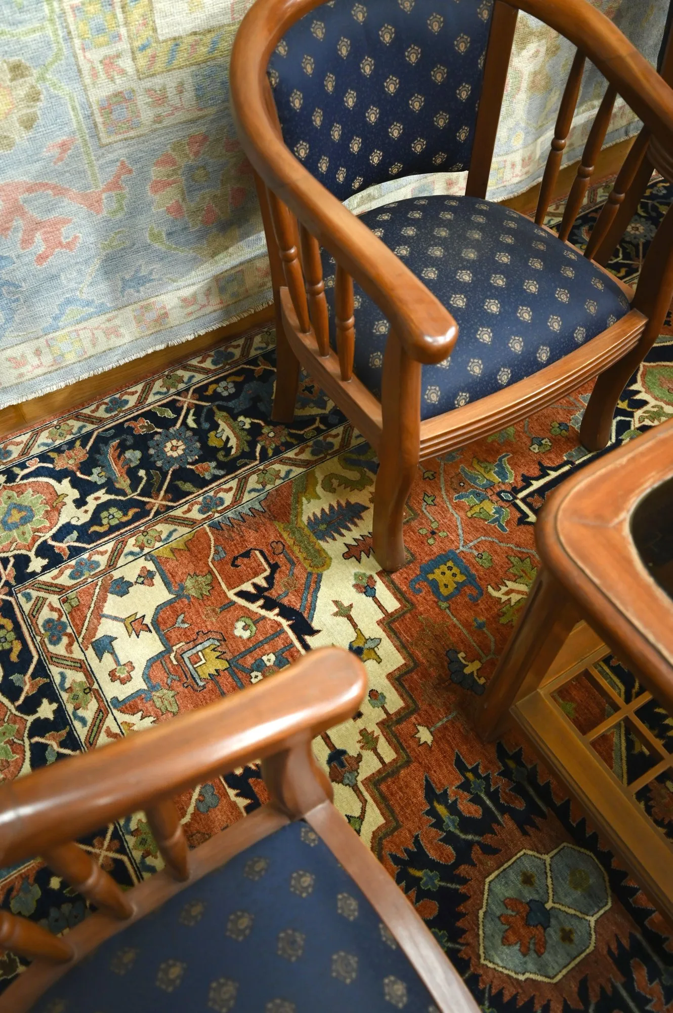 Hand-knotted rug in rust, navy and cream laid under wooden armchairs